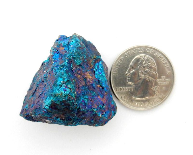 One large Peacock Ore rough stone next to quarter for size comparison 