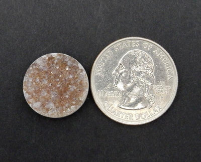 round druzy cabochon next to a quarter for size reference on black background