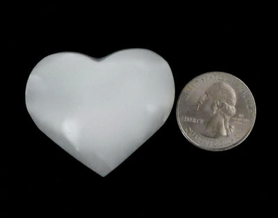 Selenite Heart Shaped Stone next to a quarter for size