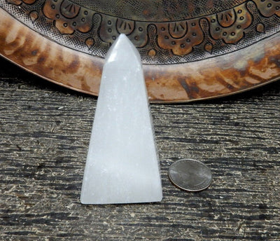 close up of one selenite obelisk with quarter for size reference