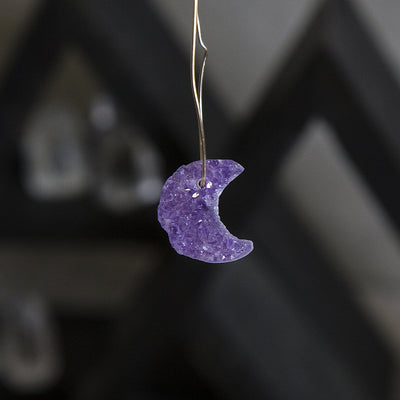 One amethyst moon hanging from a gold wire to show the drilled hole on top.