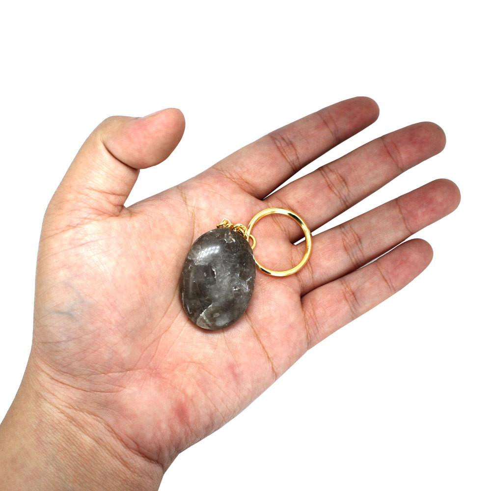 one smokey quartz worry stone keychain in hand for size reference