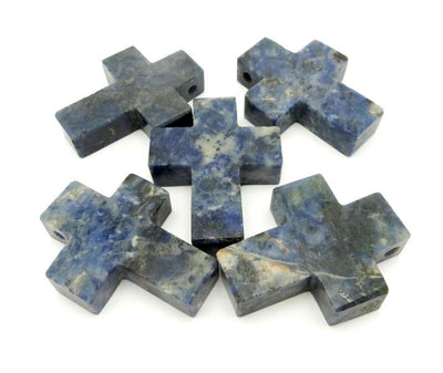 five sodalite crosses in a pile on white background