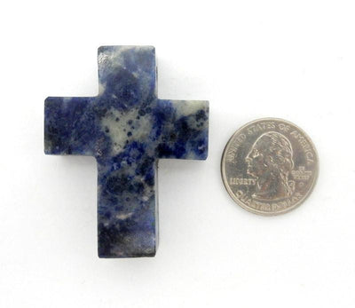 one sodalite cross on white background with quarter for size reference