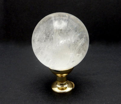 up close shot of Crystal Quartz Sphere on Gold Tone on black background