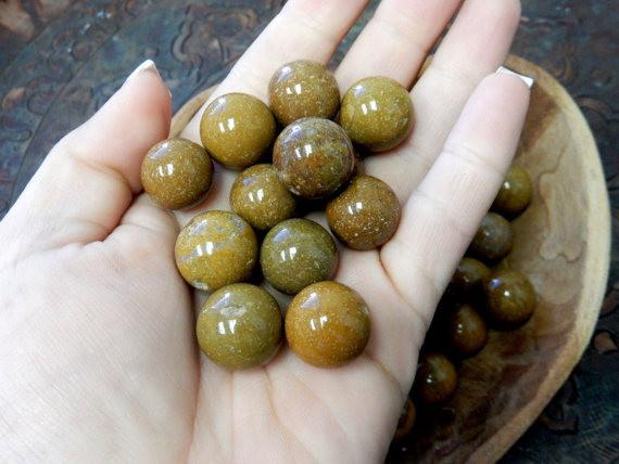 hand holding up yellow jasper spheres with more in the background