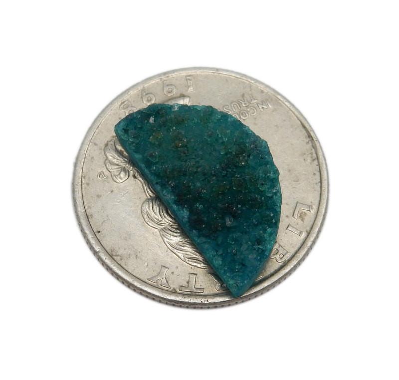 half of a pair  of the Teal Green Half Moon Druzy stones on a quarter for sizing.