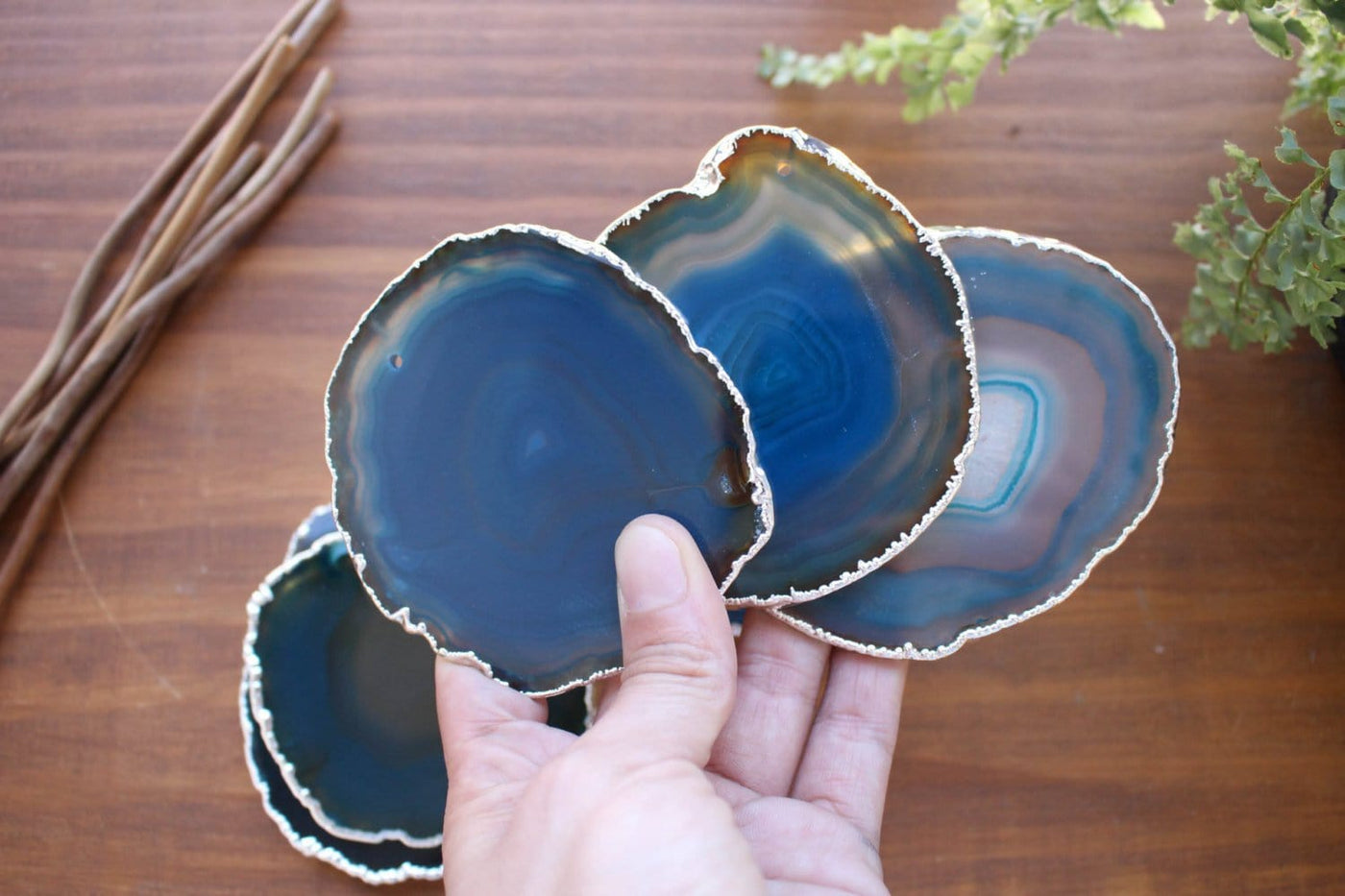 A hand holding 3 silver electroplated  Teal Top Drilled Agate Slices . Those agate slices measure between 3-3.5" in diameter. and have an average weight of 0.15 lb