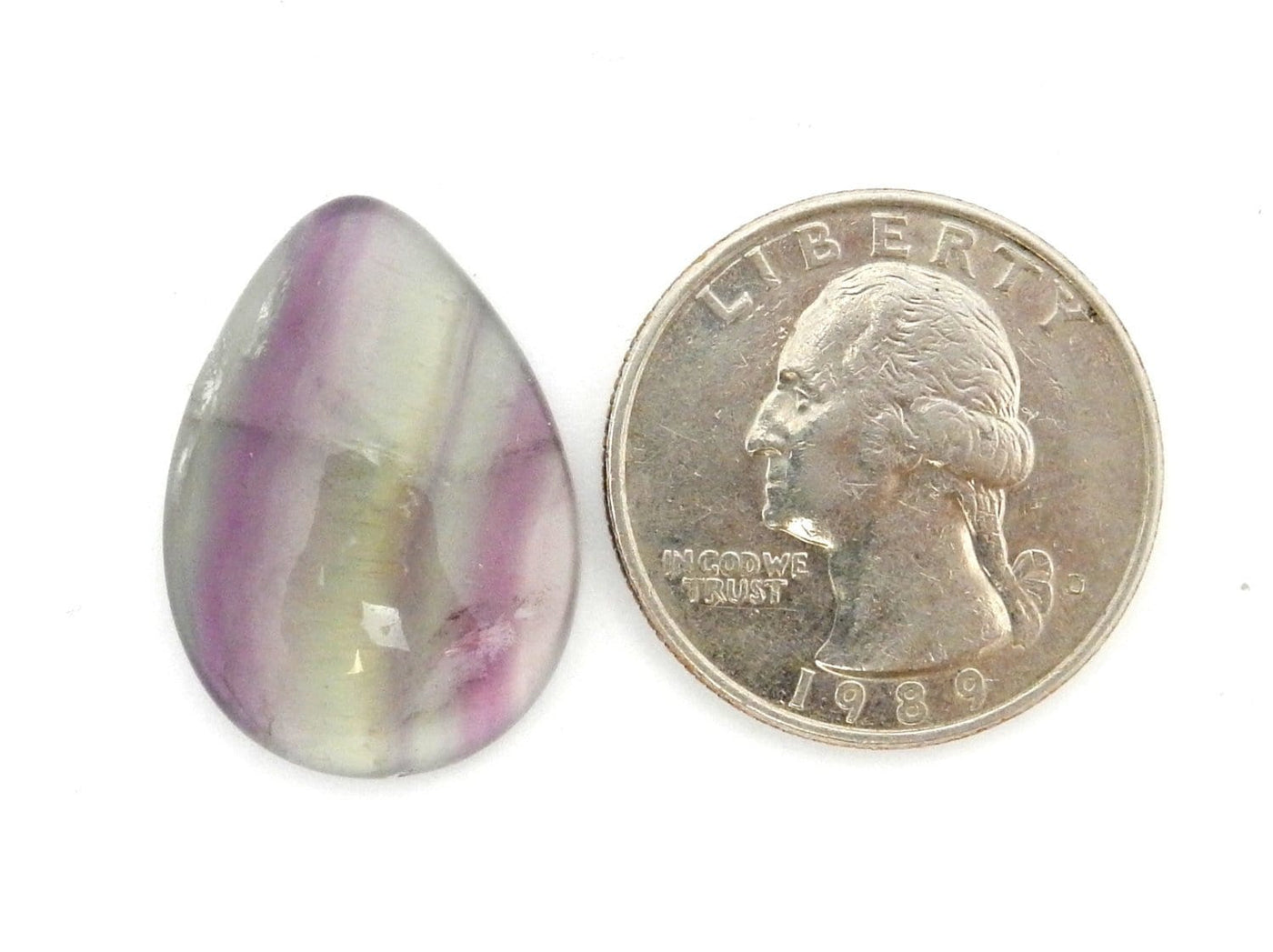 Teardrop Shaped Fluorite Cabochon next to a quarter for sizing, Approximate sizing is 25mm x 18 mm
