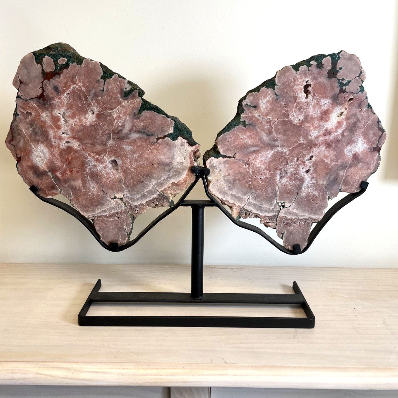 Large pink amethyst wings on a black metal stand and on a table.