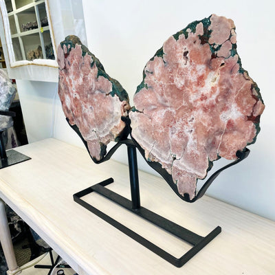 Large pink amethyst wings on a black metal stand and on a table.
