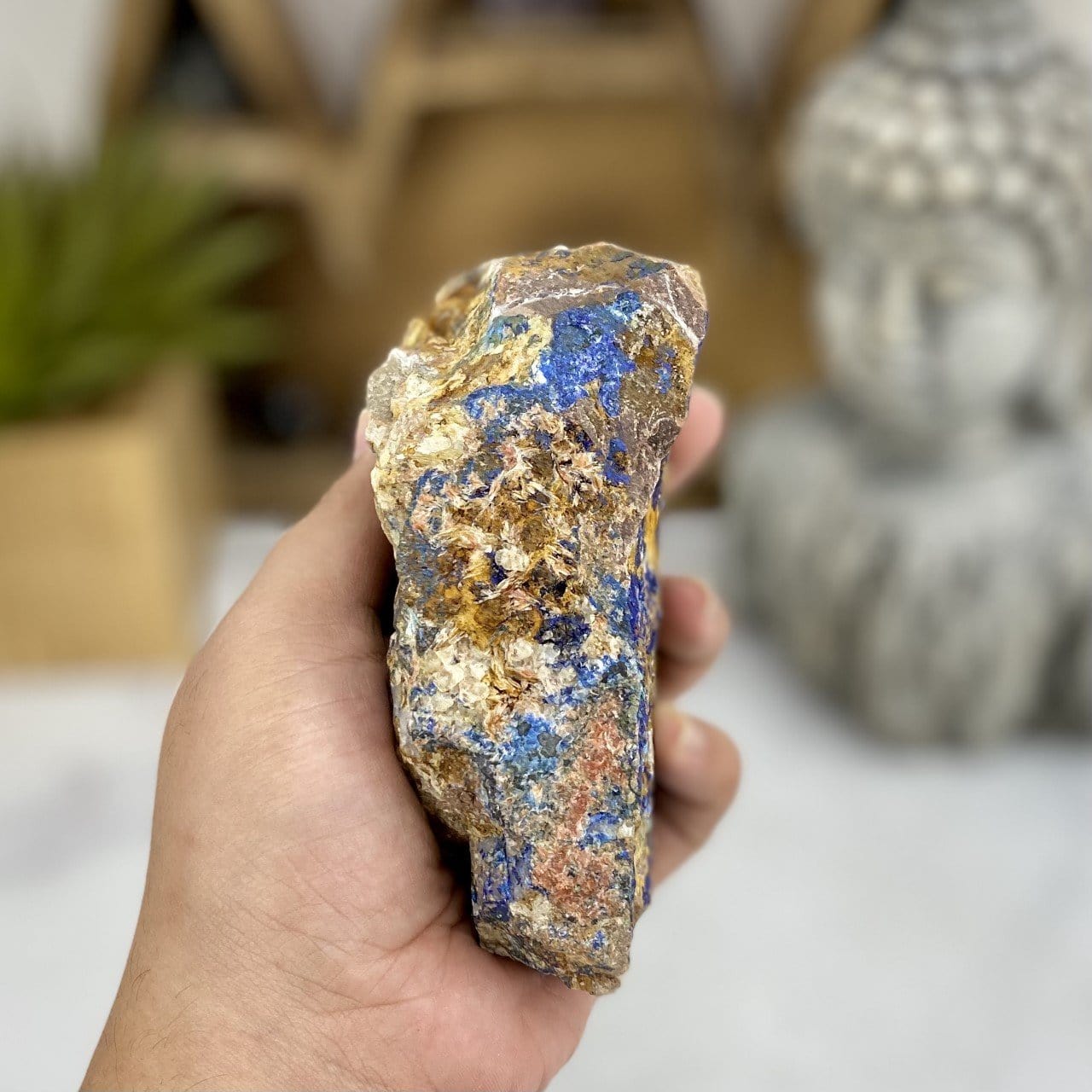 Hand holding up Raw Azurite with Malachite with decorations blurred in the background