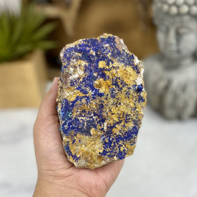 Hand holding up Raw Azurite with Malachite with decorations blurred in the background