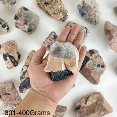 One piece of Feldspar with Black Tourmaline in the hand showing the weight of 301-400grams.