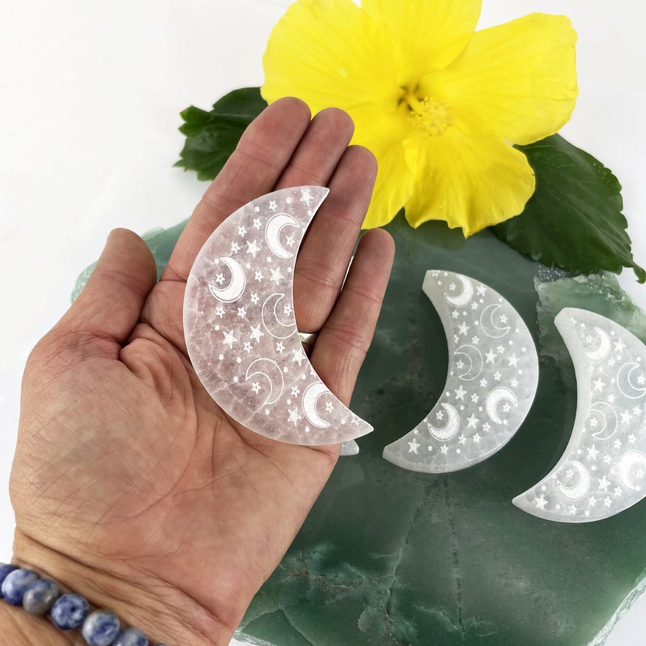selenite engraved crescent moon charging plate in hand for size reference with others on display in background