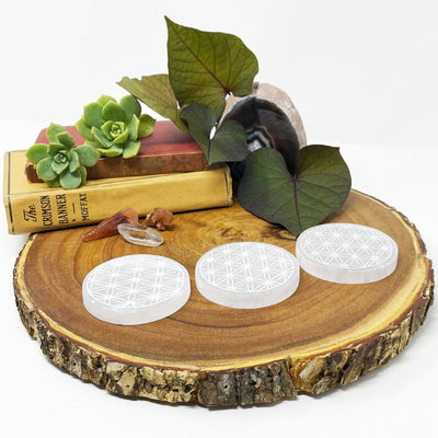 side view of three selenite round plates engraved with flower of life on display for thickness