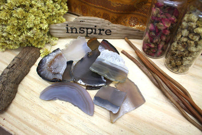 Tumbled Natural Agate Slices on a wooden background with a piece of wood saying "inspire" in the back.