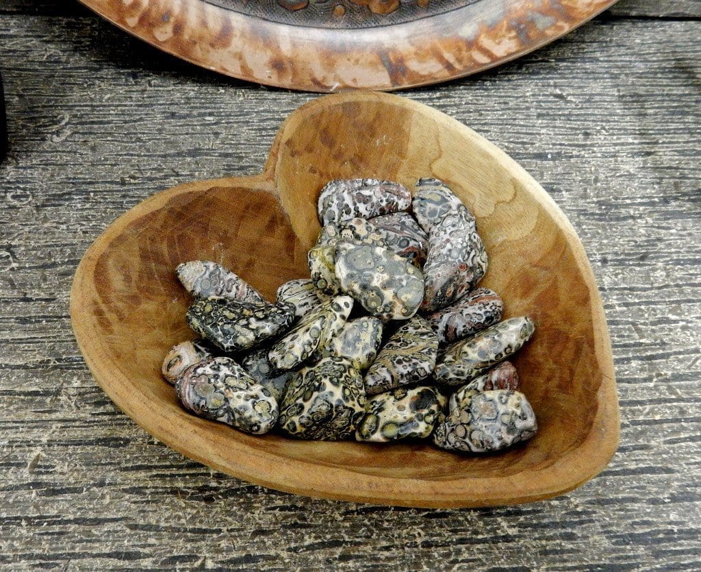 A pile of tumble jasper stones in a wooden heart bowl 