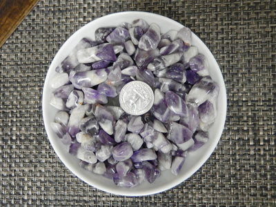 half pound of chevron amethyst small tumbled stones displayed next to a quarter for size reference 