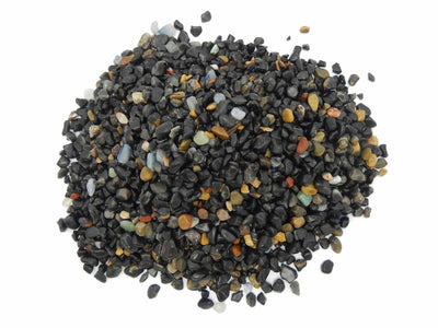 Black onyx chips on a white background.  They are mixed with a few other colorful stones.
