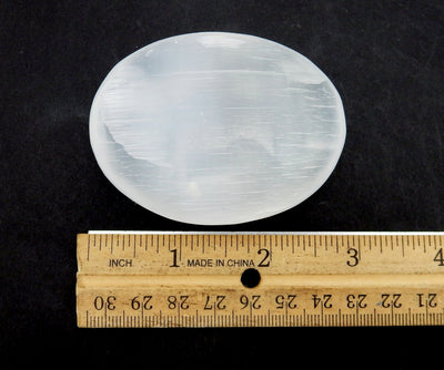 selenite palm stone with ruler for size reference 