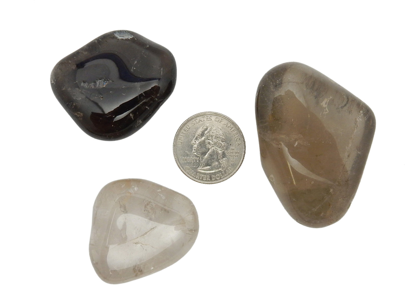 three smokey quartz tumbled gemstones on white background with quarter for size reference