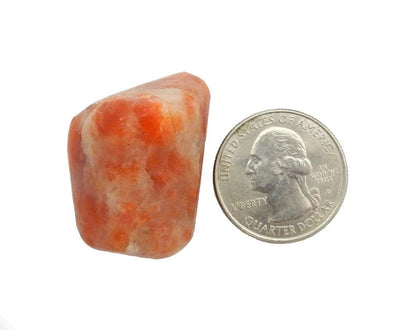 Tumbled Polished Sunstone Stone next to a quarter