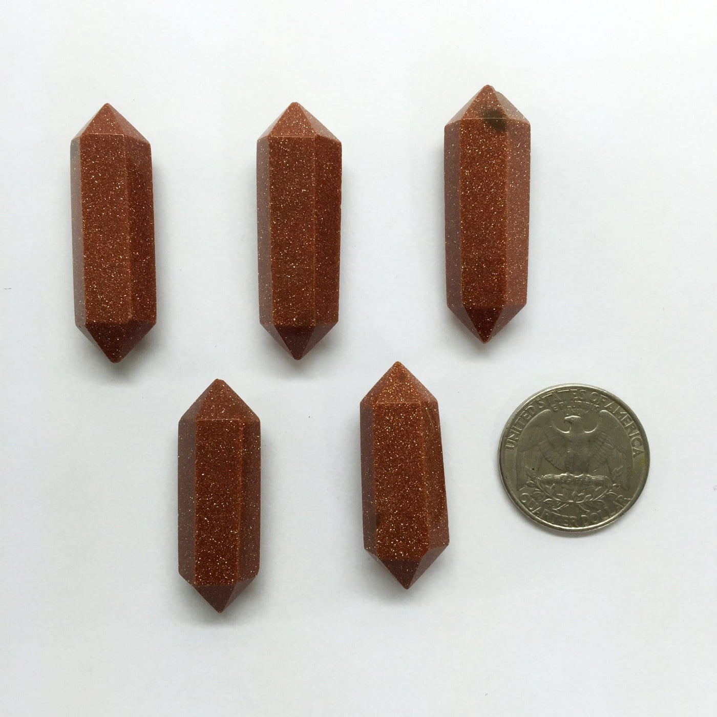 5 Goldstone Double Terminated Points on a white background with a quarter next to it as a size comparison