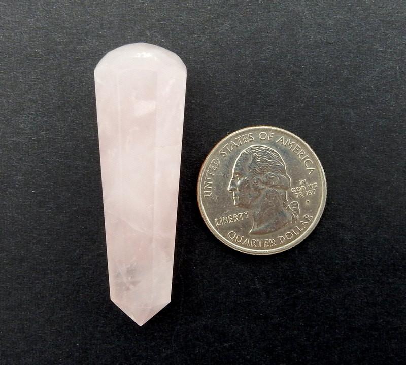 Rose Quartz Massage Wand next to a quarter for size reference on black background
