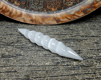 close up of spiral selenite wand with decoration in the background