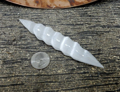 spiral selenite wand next to a quarter for size reference