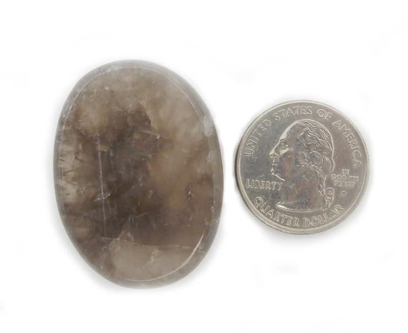 one smokey quartz worry stone on white background with quarter for size reference